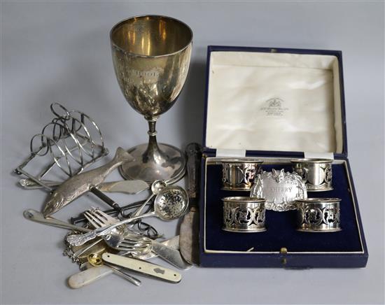A cased set of four silver napkin rings, two cast silver wine labels with hunting scenes, a silver trophy cup and other items.